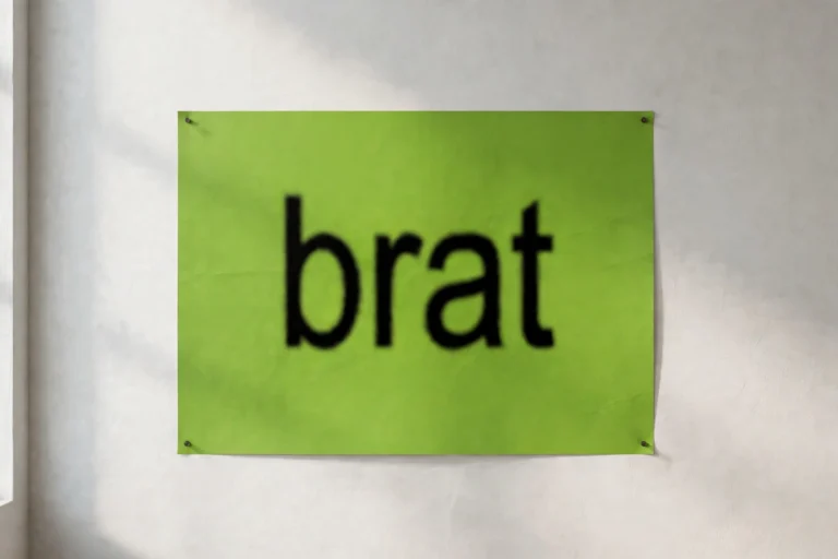 Lime green brat-style poster mockup with blurry bold black text reading brat pinned on a white studio wall