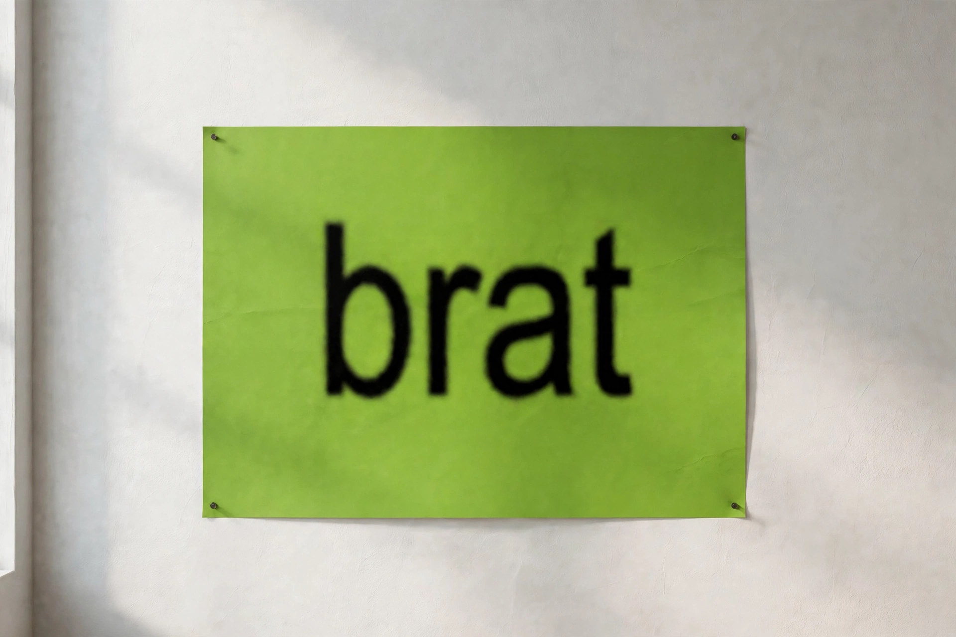 Lime green brat-style poster mockup with blurry bold black text reading brat pinned on a white studio wall